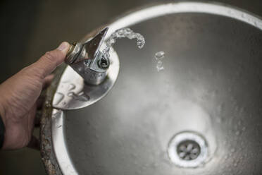 Cropped Hand Drücken Wasserhahn Taste des Trinkbrunnens - EYF06956