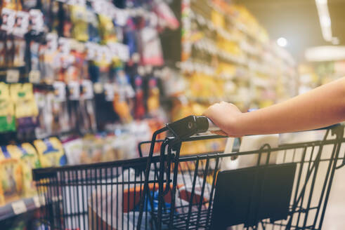 Cropped Hand der Frau hält Einkaufswagen im Supermarkt - EYF07033