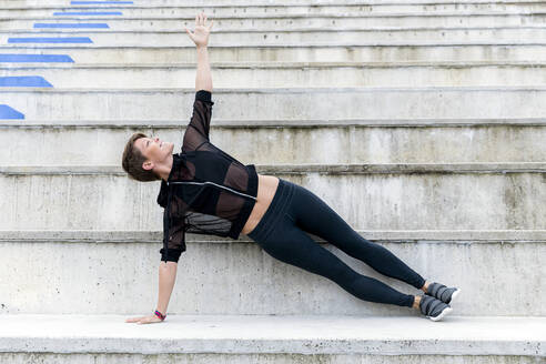 Sportliche Frau beim Training auf der Treppe, seitliche Planke - LVVF00061