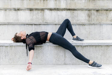 Athletic woman during break after workout on stairs - LVVF00062