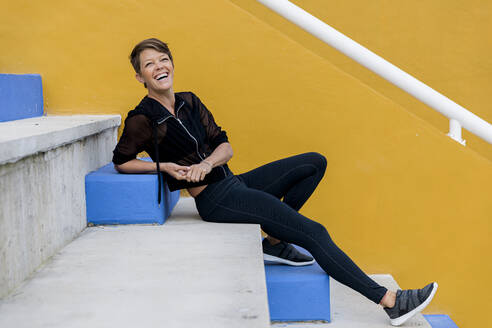 Laughing athletic woman sitting on stairs - LVVF00082
