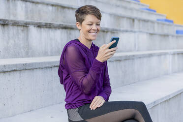 Lächelnde, sportliche Frau mit Smartphone - LVVF00089
