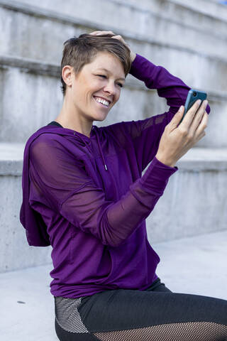 Sportliche Frau, die ein Smartphone benutzt und ein Selfie macht, lizenzfreies Stockfoto