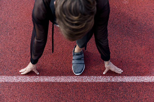 Athletic woman at starting line on tartan track, from above - LVVF00102