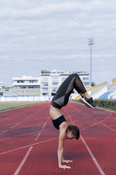 Athletic woman doing handstand on tartan track - LVVF00108