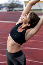 Athletic woman stretching on tartan track - LVVF00112