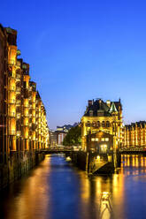 Deutschland, Hamburg, Beleuchtetes Wasserschloss in der Speicherstadt in der Abenddämmerung - PUF01924