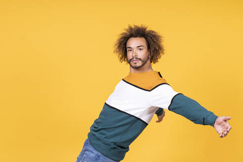 Cool young man with curly hair dancing against yellow background - SNF00345