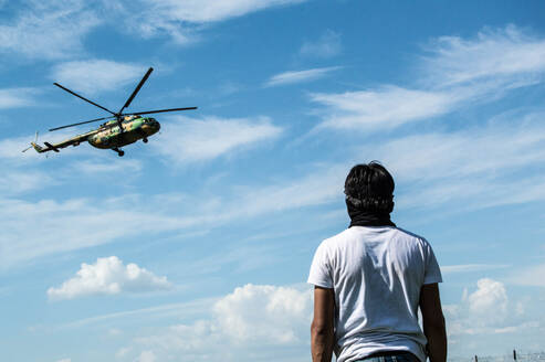 Rückansicht eines Mannes mit Blick auf einen Hubschrauber - EYF07102