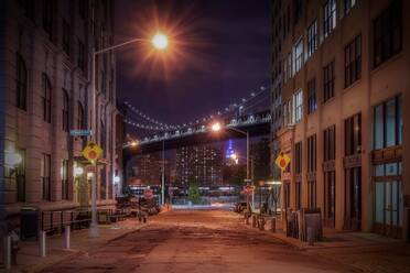 Straße inmitten beleuchteter Gebäude gegen Manhattan Bridge bei Nacht - EYF07105