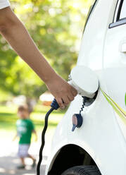 Cropped Hand Of Person Charging White Electric Car - EYF07111