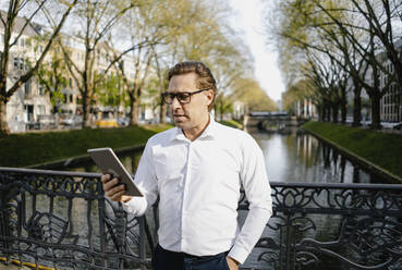Geschäftsmann mit Tablet in einem Kanal in der Stadt - JOSEF00808