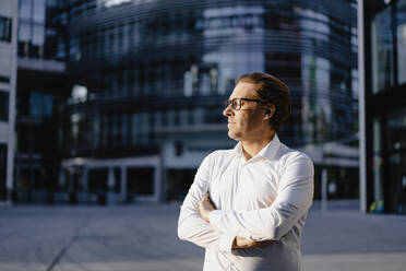 Businessman with closed eyes in sunshine in the city - JOSEF00821