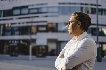 Businessman with closed eyes in sunshine in the city - JOSEF00824