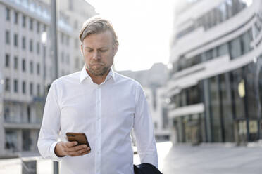 Businessman using smartphone in the city - JOSEF00845