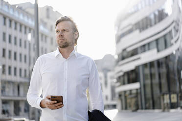 Businessman with smartphone in the city - JOSEF00846