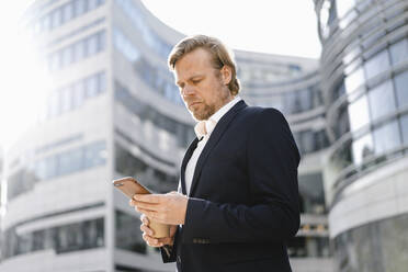 Businessman using smartphone in the city - JOSEF00849