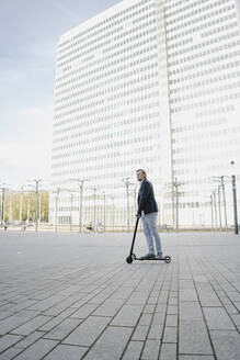 Geschäftsmann fährt Kick-Scooter auf Stadtplatz - JOSEF00870