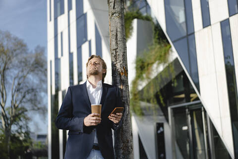 Geschäftsmann mit Kaffee zum Mitnehmen und Smartphone in der Stadt, lizenzfreies Stockfoto