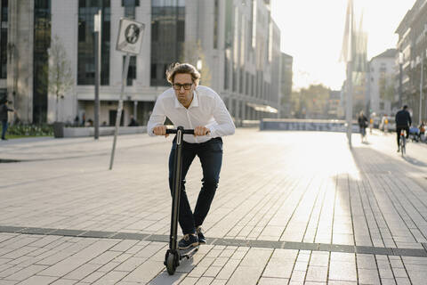 Geschäftsmann fährt Kick-Scooter in der Stadt, lizenzfreies Stockfoto