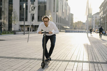 Geschäftsmann fährt Kick-Scooter in der Stadt - JOSEF00891