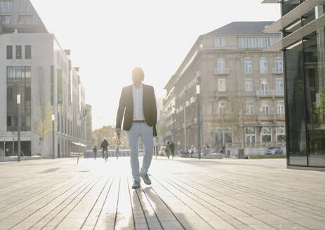 Geschäftsmann beim Spaziergang in der Stadt bei Sonnenuntergang - JOSEF00899