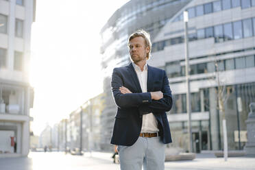 Businessman standing in the city looking sideways - JOSEF00901