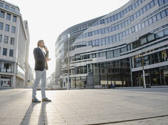 Geschäftsmann am Telefon in der Stadt bei Sonnenuntergang - JOSEF00906