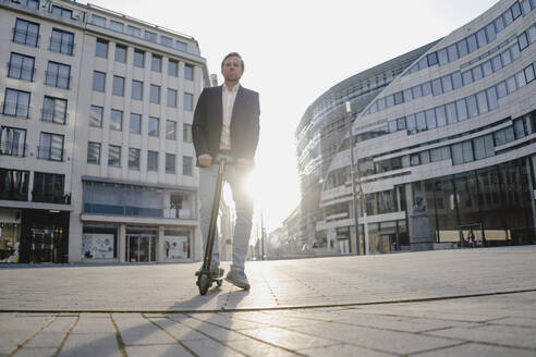 Geschäftsmann mit Kick-Scooter in der Stadt bei Sonnenuntergang - JOSEF00911
