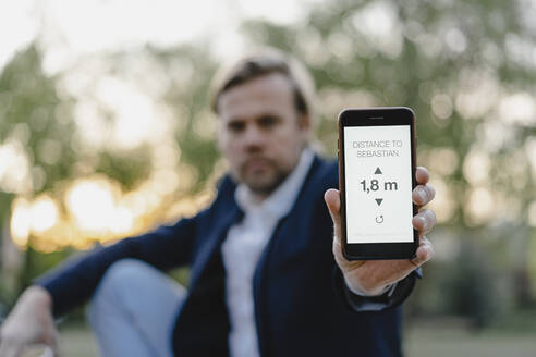 Nahaufnahme eines Geschäftsmannes, der ein Smartphone hält und die Entfernung auf dem Display anzeigt - JOSEF00933