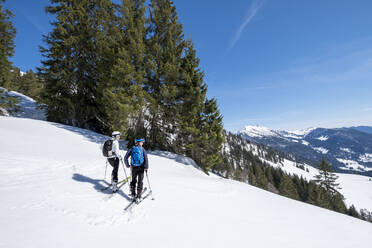 Mutter und Sohn beim Skifahren auf einem verschneiten Berg gegen den Himmel, Berchtesgaden, Bayern, Deutschland - HAMF00639