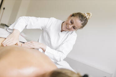 Cupping therapy, female alternative practitioner applying oil for treatment at back - DAWF01694