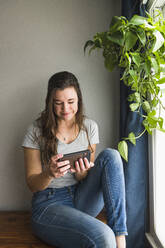Smiling portrait of Individual Woman On her phone at home - CAVF85538