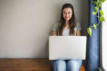 Smiling portrait of Individual Woman On her laptop at home - CAVF85539