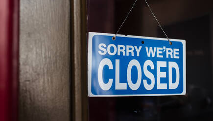 Close up of a closed sign hanging in the window of a store. stock