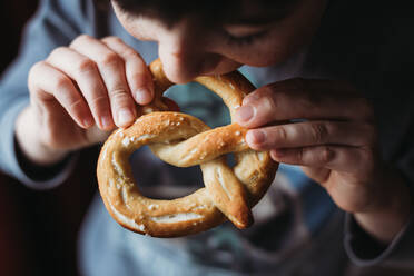 Close up of boy eating a soft homemade pretzel. - CAVF85562