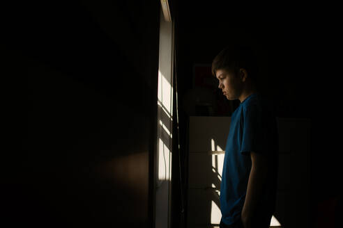 Junger Teenager, der während der Isolation aus dem Fenster schaut - CAVF85583