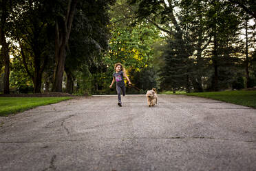 Mädchen läuft mit Hund an der Leine - CAVF85627