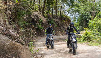 Zwei Freunde fahren mit ihren Scrambler-Motorrädern durch den Wald - CAVF85634