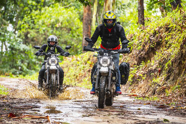 Zwei Freunde fahren mit ihren Scrambler-Motorrädern durch den Wald - CAVF85636