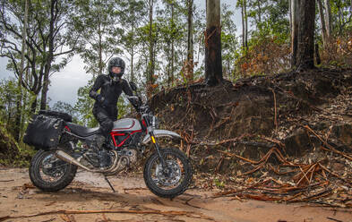 Frau posiert auf ihrem Scrambler-Motorrad im thailändischen Wald - CAVF85638