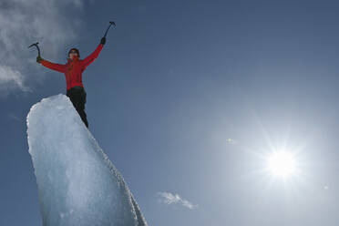 Frau klettert auf einen Eisberg in der Lagune des Fjallsjoull-Gletschers - CAVF85643