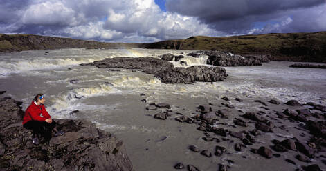 Woman admiring waterfall on the river Þjórsá in Iceland - CAVF85666