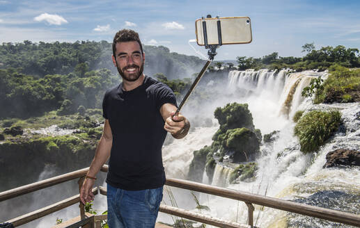 Mann macht ein Selfie mit Einbeinstativ an den Iguazu-Wasserfällen in Argentinien - CAVF85668