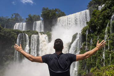 Junger Mann posiert vor den Iguacu-Wasserfällen in Argentinien - CAVF85669