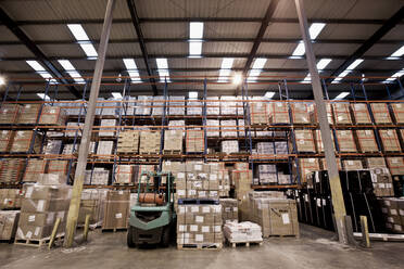 Forklift truck parked at fully stocked warehouse in London - CAVF85675