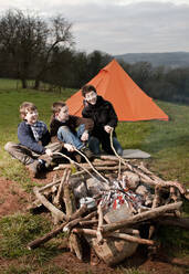 Three boys sitting at campfire in South Wales - CAVF85680