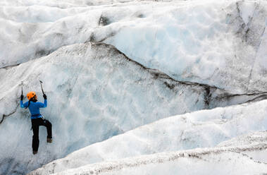 Frau klettert an der Eiswand des Sólheimajökull-Gletschers in Island - CAVF85693