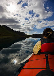 Woman rowing sea kayak on still lake in central Iceland - CAVF85722