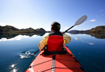 Woman rowing sea kayak on still lake in central Iceland - CAVF85723